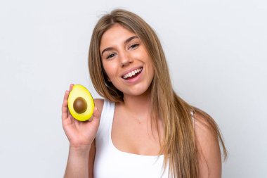 Beyaz arka planda izole edilmiş beyaz bir kadın elinde bir avokado tutarken gülümsüyor. Portreyi kapat