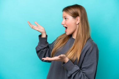 Mavi arka planda mahsur kalmış beyaz bir kadın. Sürpriz bir ifadeyle yan tarafa bakarken.