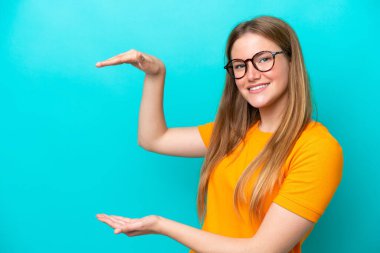 Mavi arka planda izole edilmiş beyaz bir kadın ilan vermek için kopyalama alanı tutuyor.