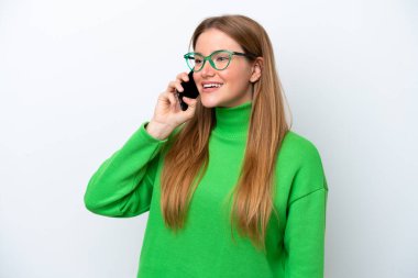 Beyaz arka planda izole edilmiş genç beyaz kadın cep telefonuyla sohbet ediyor.