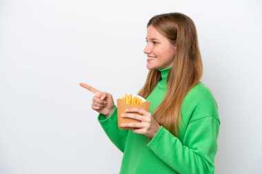 Young caucasian woman holding fried chips isolated on white background pointing to the side to present a product