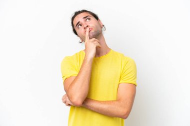Caucasian handsome man isolated on white background having doubts while looking up