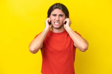 Caucasian handsome man isolated on yellow background frustrated and covering ears