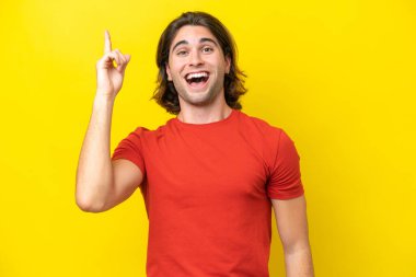 Caucasian handsome man isolated on yellow background intending to realizes the solution while lifting a finger up
