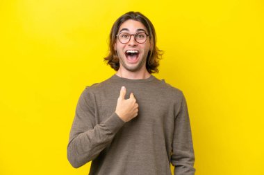 Caucasian handsome man isolated on yellow background with surprise facial expression