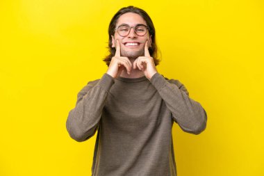 Caucasian handsome man isolated on yellow background smiling with a happy and pleasant expression