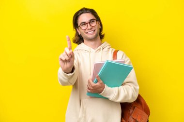 Young student handsome man isolated on yellow background showing and lifting a finger