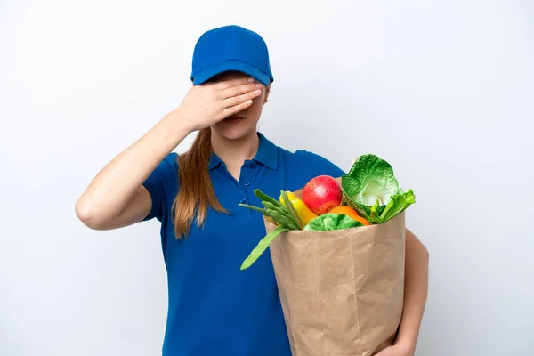 Young delivery woman taking a bag of takeaway food isolated on white background covering eyes by hands. Do not want to see something