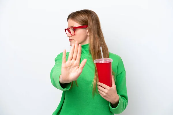 Young caucasian woman drinking soda isolated on white background making stop gesture and disappointed