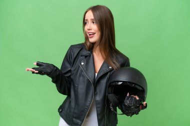 Young pretty caucasian woman with a motorcycle helmet over isolated background with surprise expression while looking side
