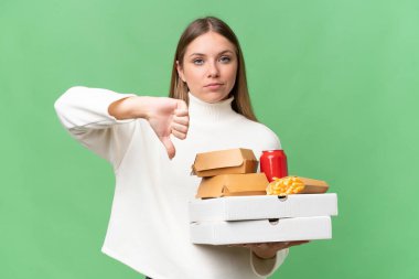 Young beautiful blonde woman holding takeaway food over isolated background showing thumb down with negative expression
