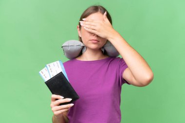 Young beautiful blonde woman with Inflatable travel Pillow over isolated background covering eyes by hands. Do not want to see something
