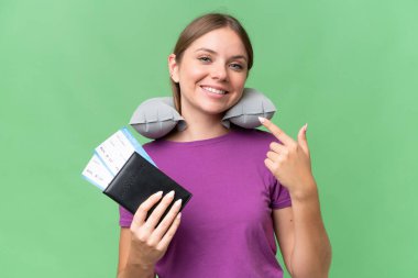 Şişirilebilir seyahat yastığı olan genç, güzel sarışın kadın izole bir arkaplanda baş parmak hareketi yapıyor.