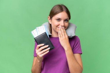 Young beautiful blonde woman with Inflatable travel Pillow over isolated background happy and smiling covering mouth with hand