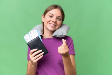 Şişirilebilir seyahat yastığı olan genç, güzel sarışın kadın izole bir arka planda para hareketi yapıyor.