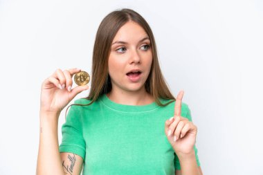 Young beautiful blonde woman holding a Bitcoin isolated on white background intending to realizes the solution while lifting a finger up