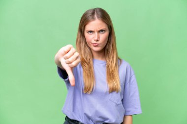 Soyutlanmış arka planda genç ve güzel bir kadın, olumsuz bir ifadeyle baş parmağını aşağı gösteriyor.