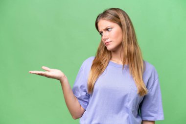 Young beautiful woman over isolated background holding copyspace with doubts