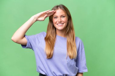 Genç, güzel bir kadın, izole bir arka planda, mutlu bir ifadeyle selamlıyor.