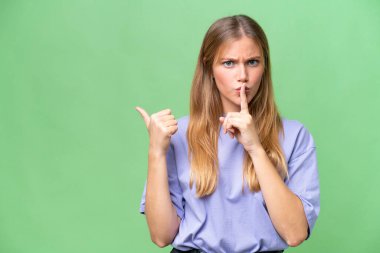 Young beautiful woman over isolated background pointing to the side and doing silence gesture