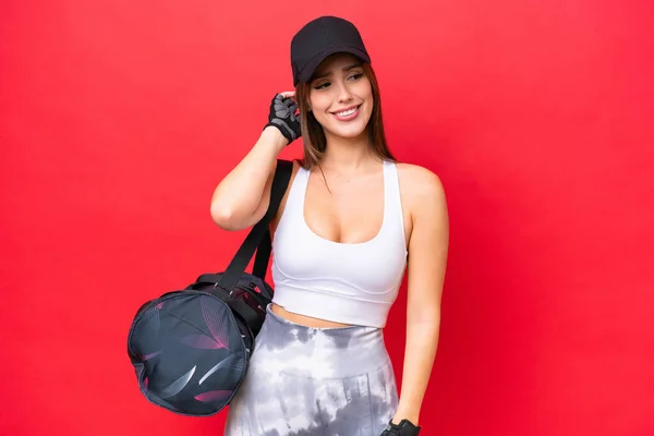 Young beautiful sport woman with sport bag isolated on red background thinking an idea