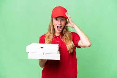 Young caucasian pizza delivery woman with work uniform picking up pizza boxes over isolated background with surprise expression