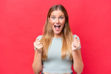 Young beautiful woman isolated on red background celebrating a victory in winner position