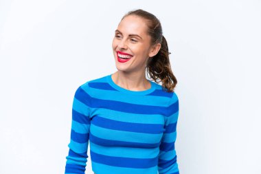 Beyaz arka planda izole edilmiş genç beyaz kadın yan bakıyor ve gülümsüyor.