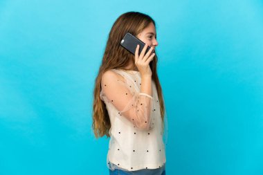 Küçük kız izole edilmiş mavi arka planda biriyle cep telefonuyla sohbet ediyor.