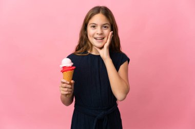 Child with a cornet ice cream over isolated pink background with surprise and shocked facial expression