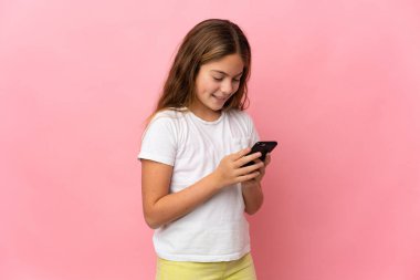 İzole edilmiş pembe arkaplan üzerindeki çocuk cep telefonuyla bir mesaj veya e- posta gönderiyor