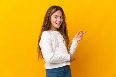 Child over isolated yellow background pointing finger to the side