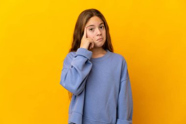 İzole edilmiş sarı arka planı olan çocuk bir fikir düşünüyor.