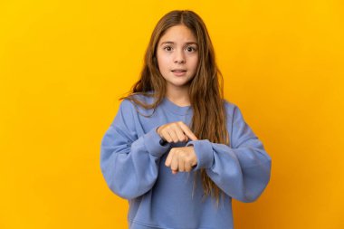 İzole edilmiş sarı arka plandaki çocuk geç kalma jesti yapıyor