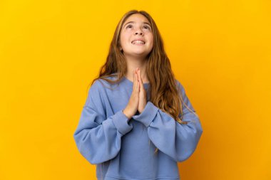 İzole edilmiş sarı arka plandaki çocuk avuç içlerini bir arada tutuyor. İnsan bir şey ister.