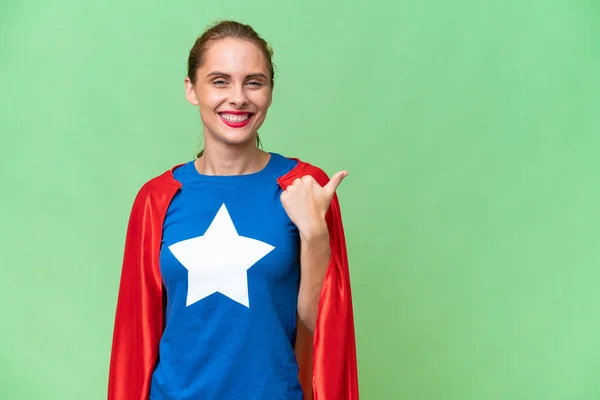 Super Hero caucasian woman over isolated background pointing to the side to present a product