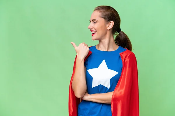 Super Hero caucasian woman over isolated background pointing to the side to present a product