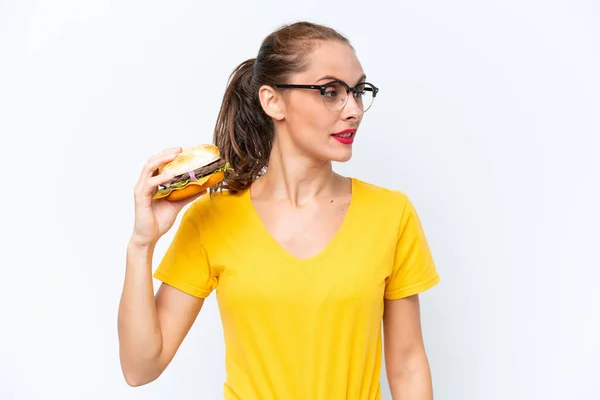 Young Caucasian Woman Holding Burger Isolated White Background Looking Side — Fotografia de Stock