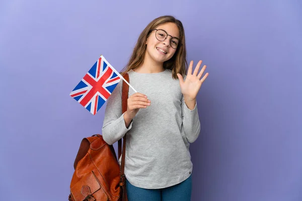 Child holding an United Kingdom flag over isolated background saluting with hand with happy expression