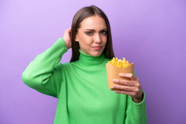 Mor arka planda kızarmış cips tutan beyaz bir kadın. Şüpheleri var.