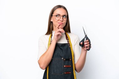 Young seamstress woman isolated on white background having doubts and thinking