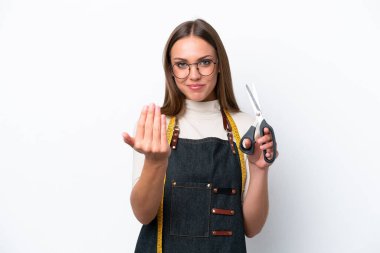 Young seamstress woman isolated on white background inviting to come with hand. Happy that you came