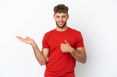 Beyaz arka planda izole edilmiş beyaz tenli yakışıklı bir adam bir reklam vermek ve onaylamak için avucunda hayali bir fotokopi makinesi tutuyor.