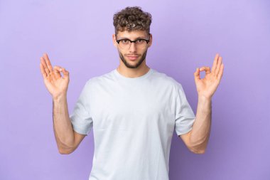 Delivery caucasian man isolated on purple background in zen pose