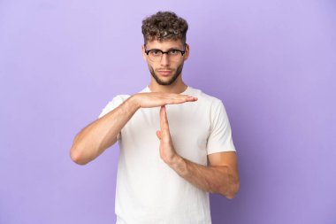 Delivery caucasian man isolated on purple background making time out gesture
