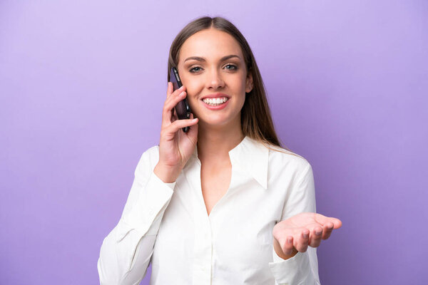 Young caucasian woman isolated on purple background keeping a conversation with the mobile phone with someone