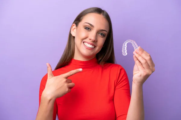 Young caucasian woman holding invisible braces and pointing it
