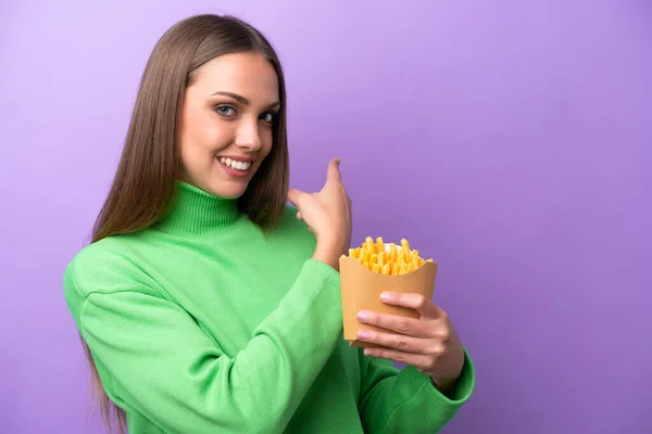 Young Caucasian Woman Holding Fried Chips Purple Background Pointing Back — Stockfoto