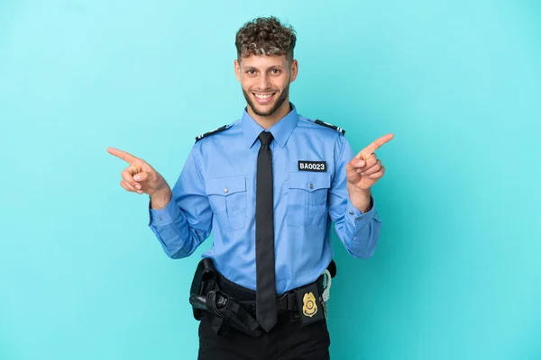 Young police blonde man isolated white on blue background pointing finger to the laterals and happy