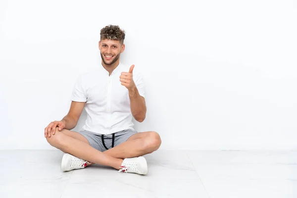 Young Blonde Man Sitting Floor Isolated White Background Thumbs Because — 스톡 사진